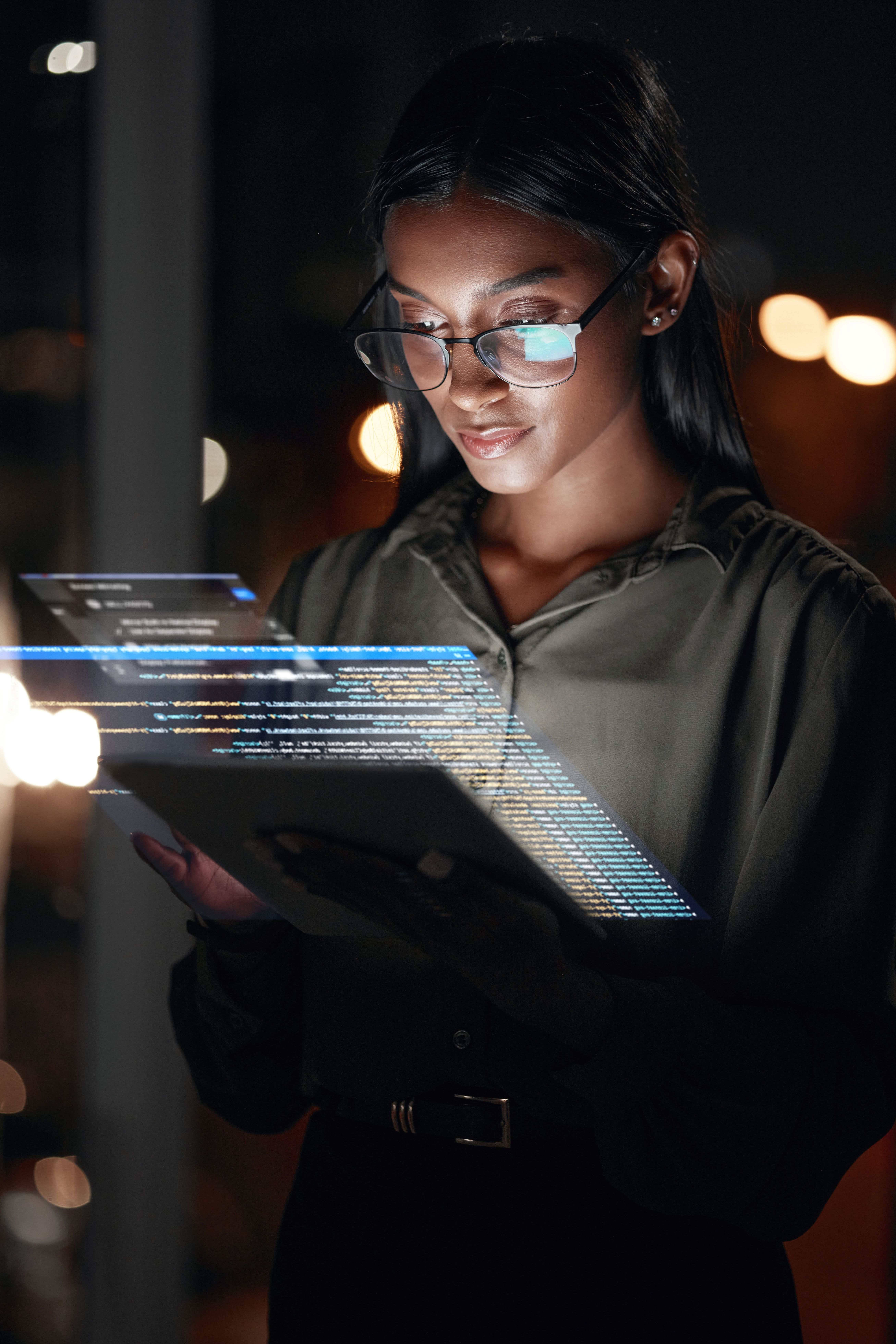 Woman looking at a tablet while data is projected off of it