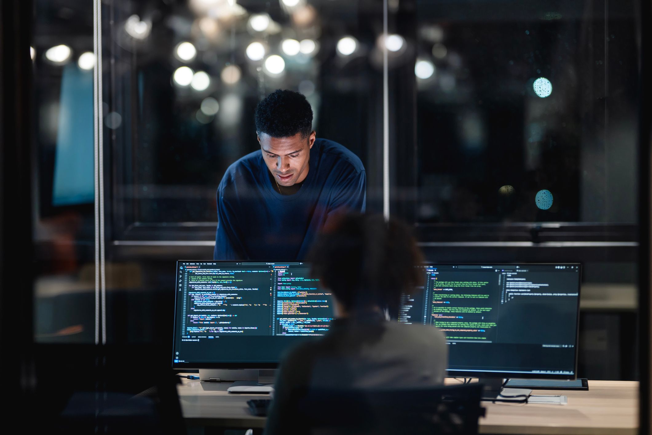 IT professional looking over a monitor in a modern office space