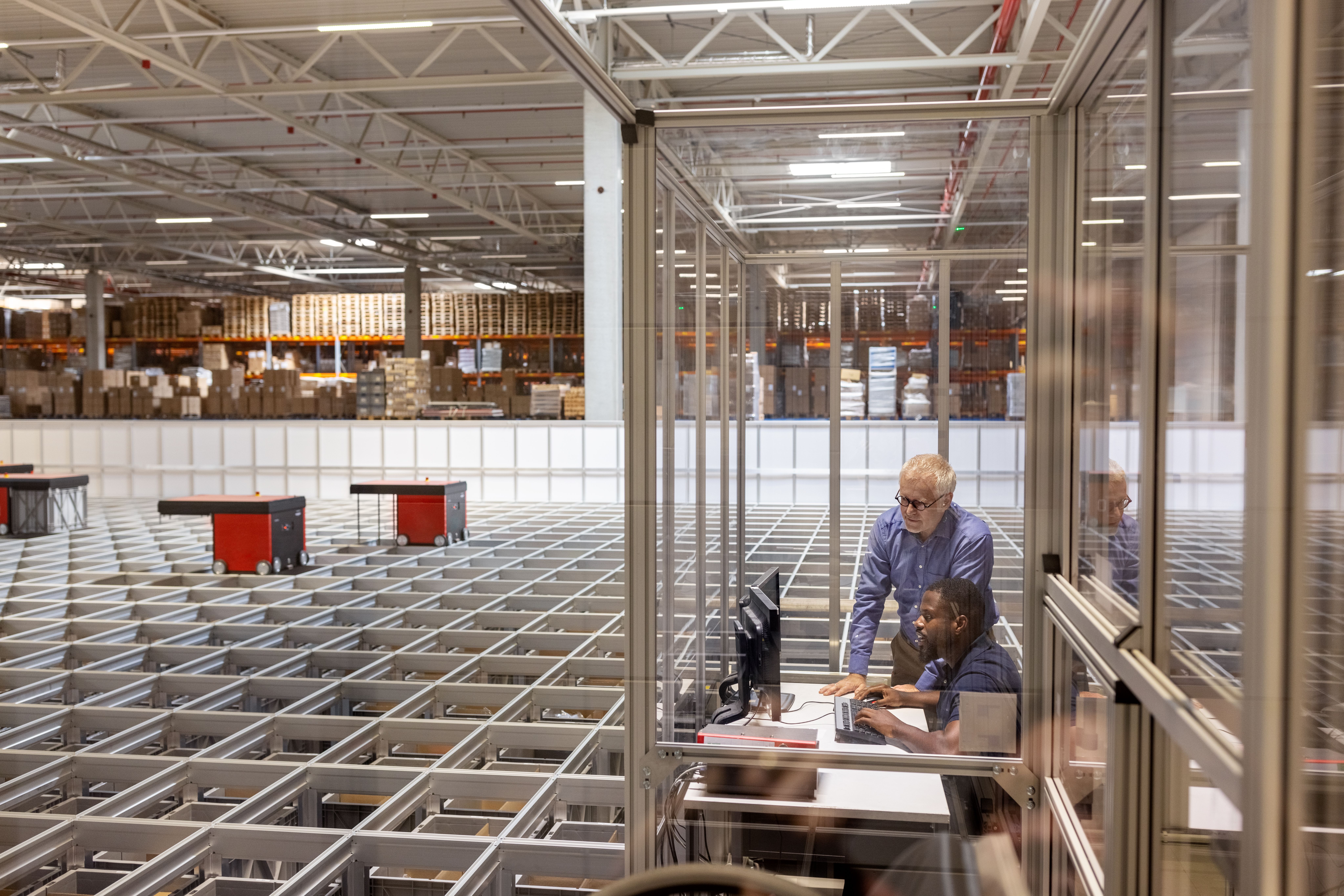 Two people overseeing a warehouse of autonomous robots