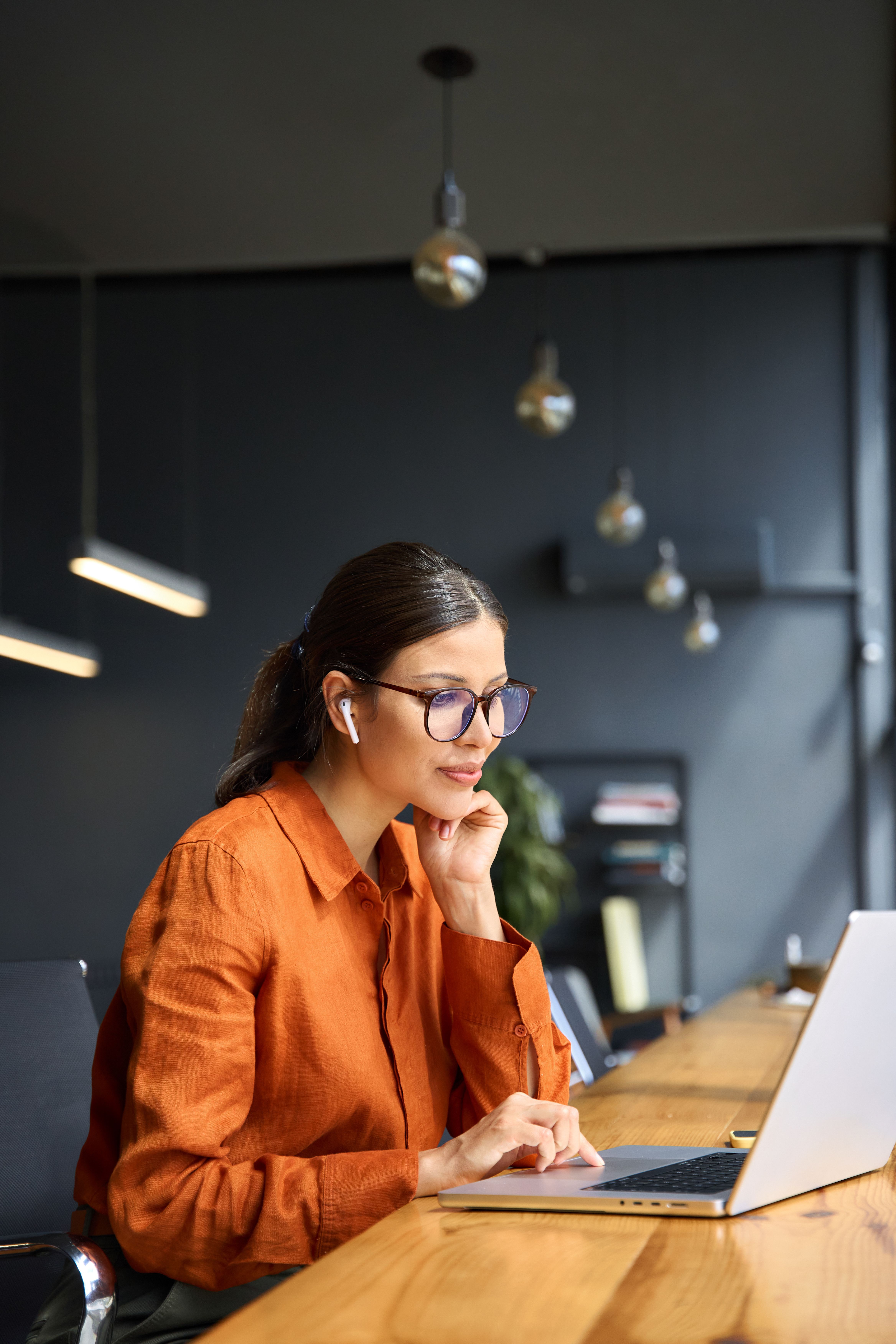 Female office worker working on a laptop in front of a window