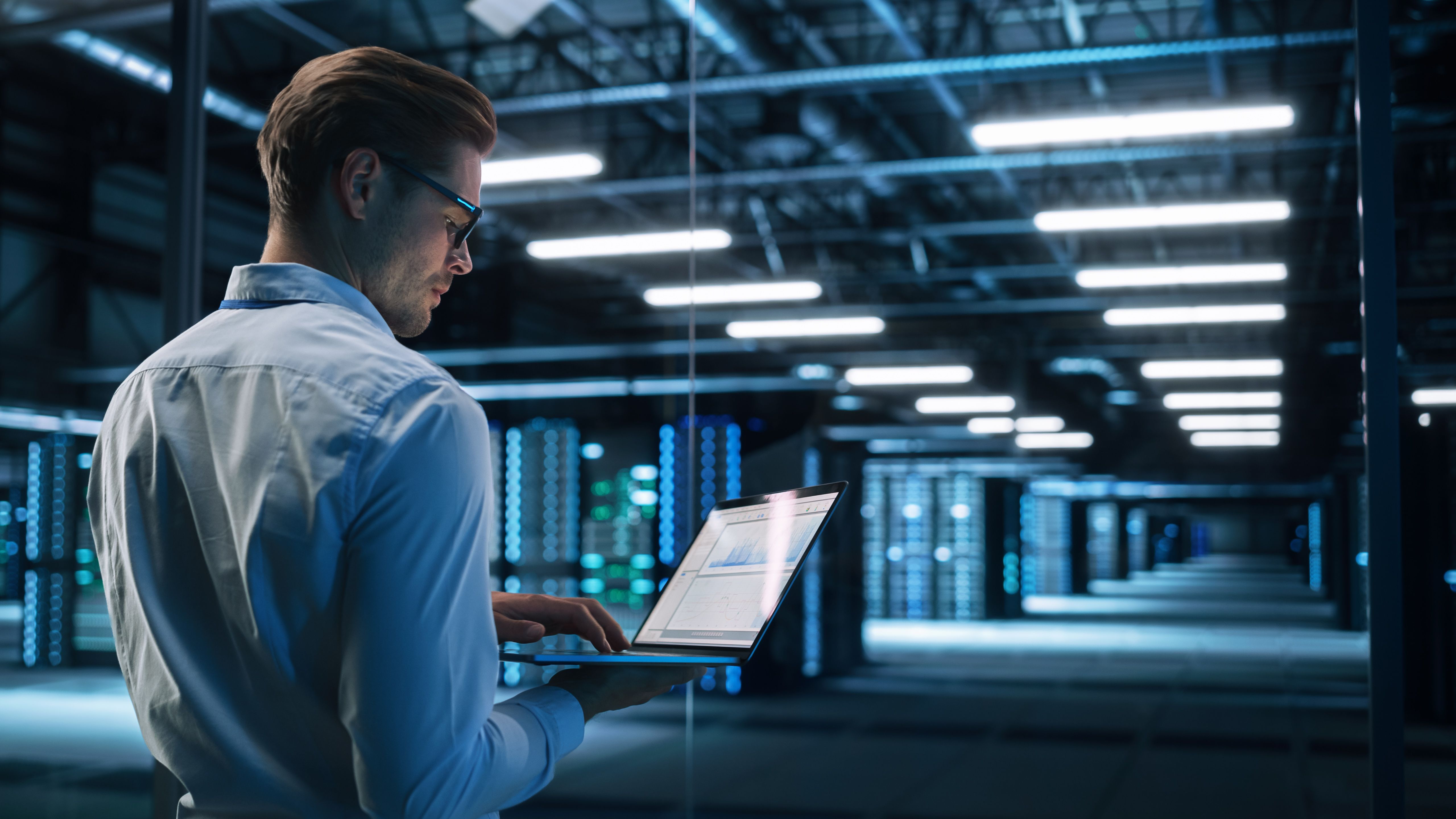Person looking at a computer in a server warehouse 