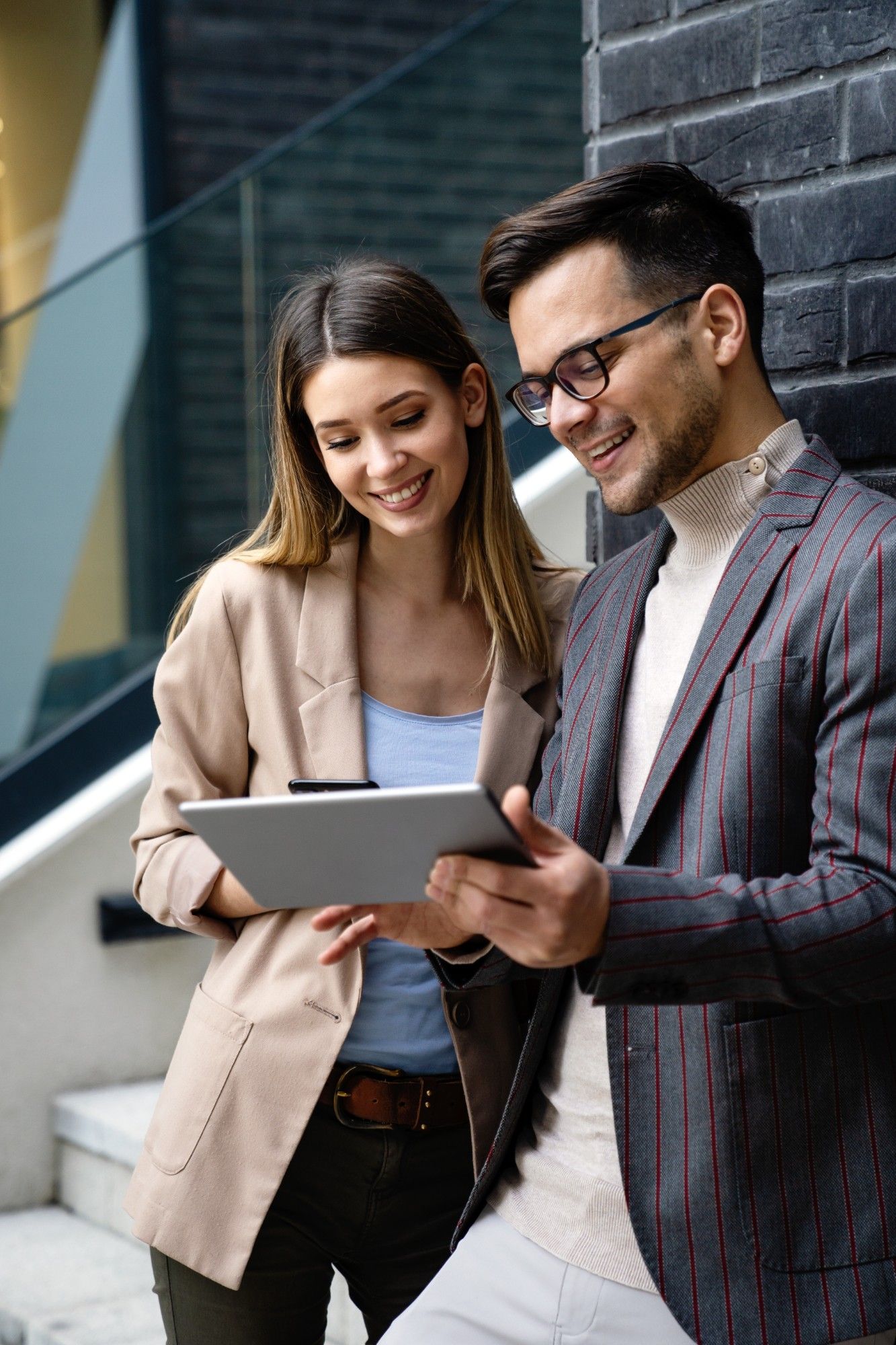 Smiling woman and man in business attire reviewing information on a tablet together in an office